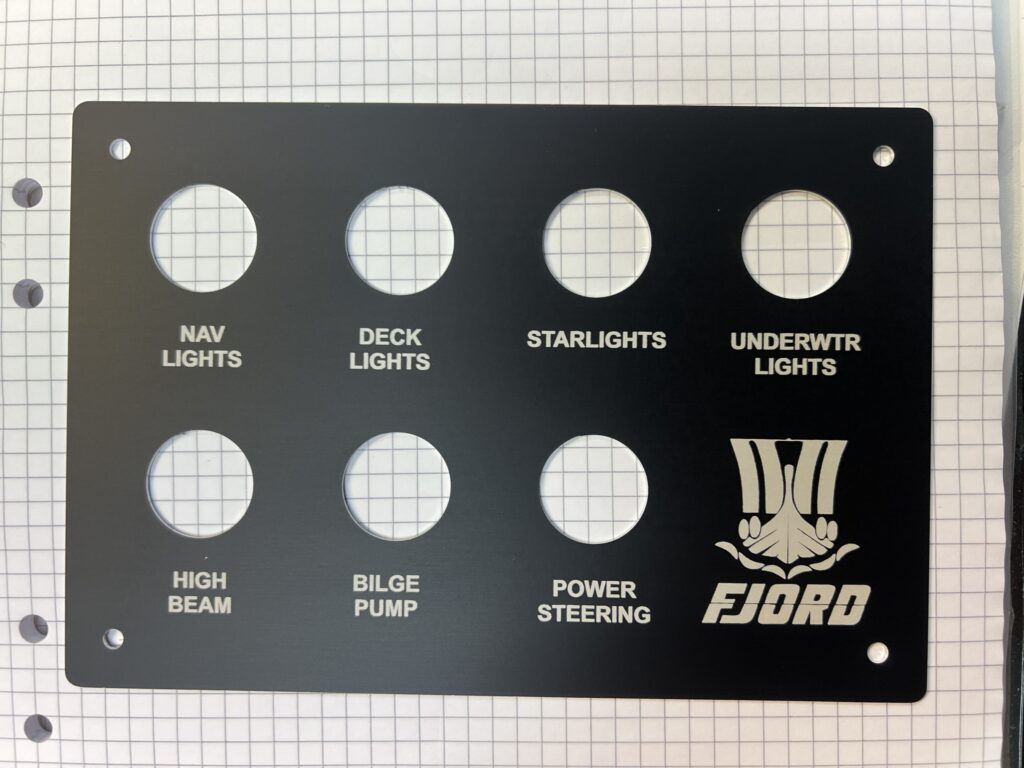 Graverad svart aluminiumpanel för Fjord båt med knappar och logotyp.